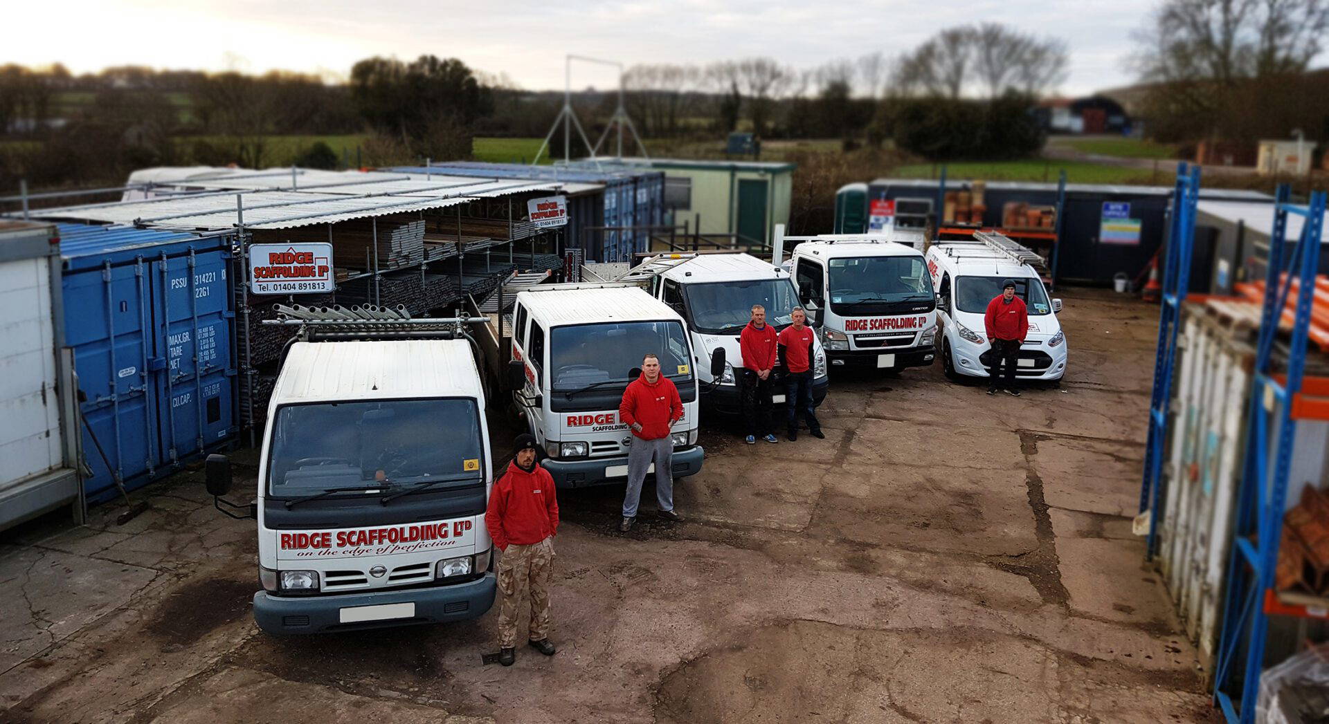 An image of multiple Ridge Scaffolding trucks. In front are 5 employees who work for the company.